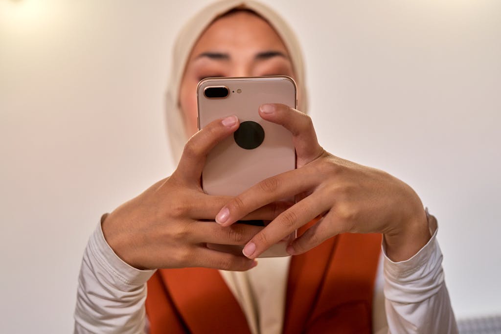 Close-up of a young woman using a smartphone indoors with a focused expression.